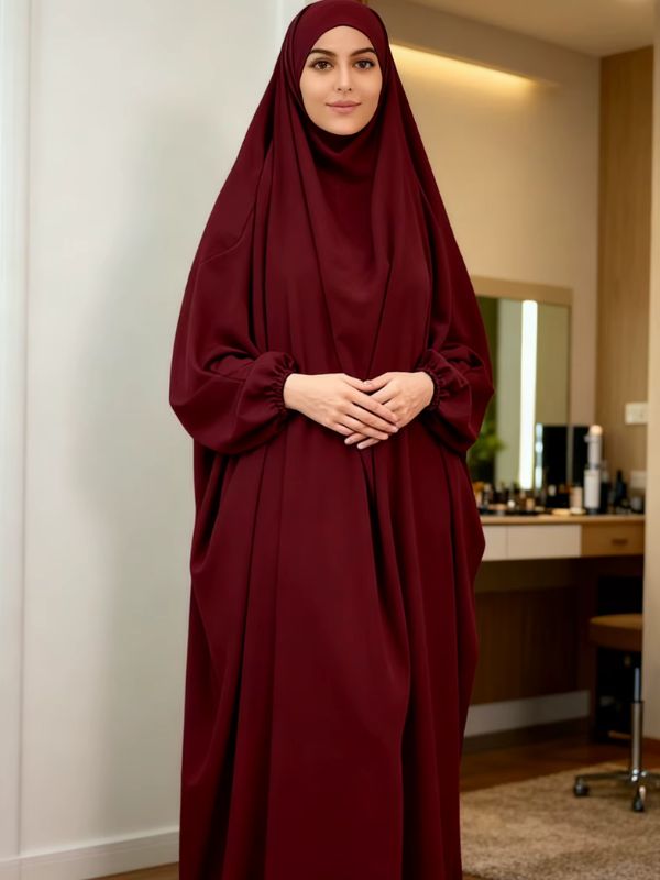 Jilbab femme une pièce bordeaux à capuche intégrée, manches larges aux poignets froncés, vue de face, mains jointes