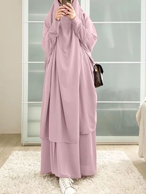 Une femme prend une photo miroir en portant un jilbab rose poudré long et fluide