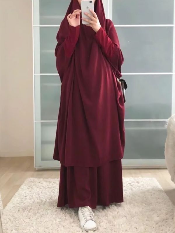 Une femme porte un jilbab rouge rubis ample et fluide.