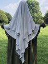 Khimar à trois voiles gris clair porté en extérieur, mettant en valeur un look modeste