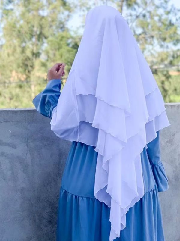 Une femme portant un khimar 3 voiles en mousseline blanc plissé, vu de dos