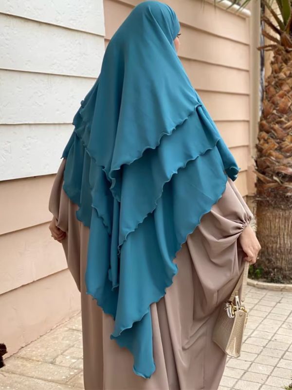 Une femme porte un khimar bleu canard à trois voiles