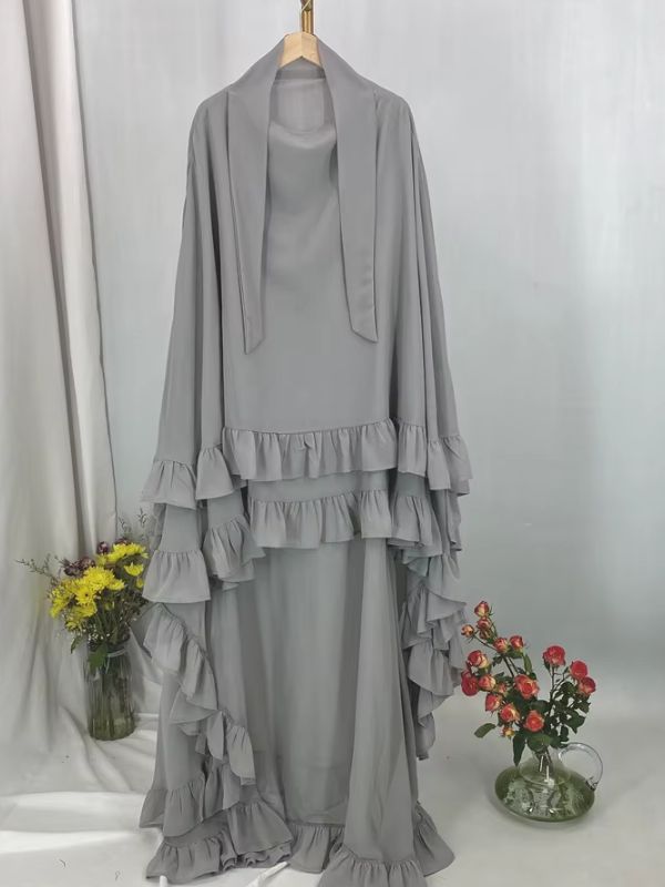 Khimar long à volants étagés gris clair présenté sur cintre, vue de face avec deux lanières au col