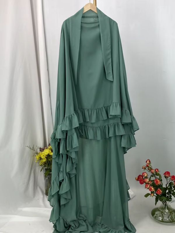 Khimar long à volants étagés vert sauge présenté sur cintre, vue de face avec deux lanières au col