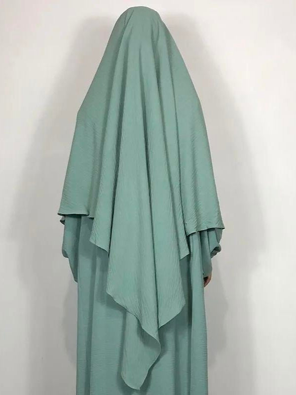 Une femme à l'allure gracieuse porte un khimar vert clair