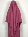 Femme en khimar violet devant un mur