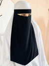 Femme qui porte une robe blanche et également un niqab noir