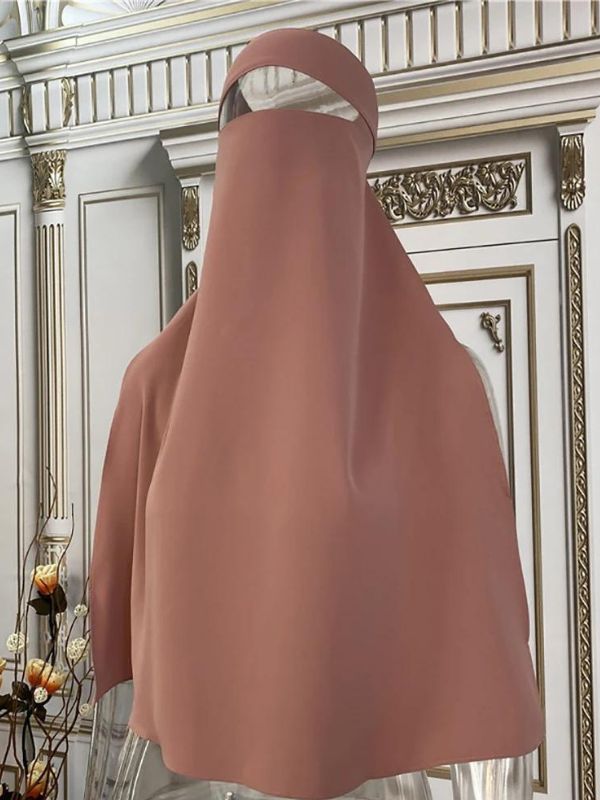 Niqab en soie de médine rose, délicatement posé sur un mannequin transparent