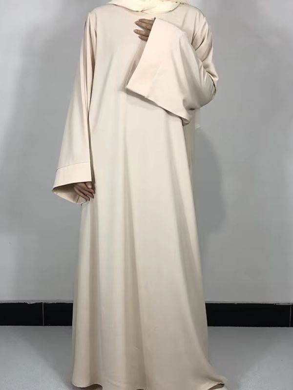 Une femme porte une robe abaya beige