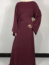 Une femme porte une abaya de couleur bordeaux