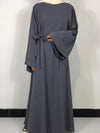 Une femme porte une robe abaya grise