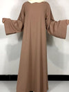 Une femme porte une robe abaya marron