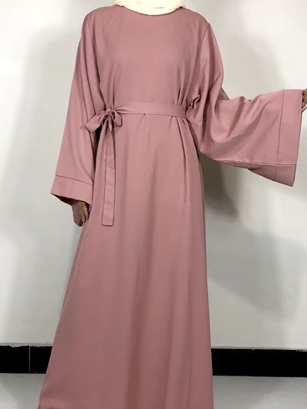 Une femme porte une robe abaya rose