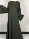 Une femme porte une robe abaya vert foncé