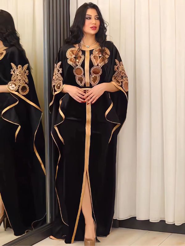 Une femme porte une robe caftan noire, devant un miroir