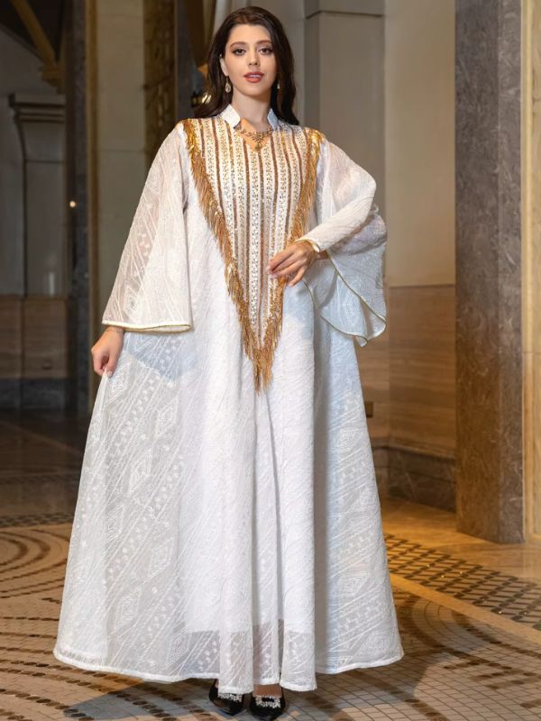 Robe marocaine blanche Lumière de Fès vue de face, main posée sur le plastron orné de paillettes et de franges dorées