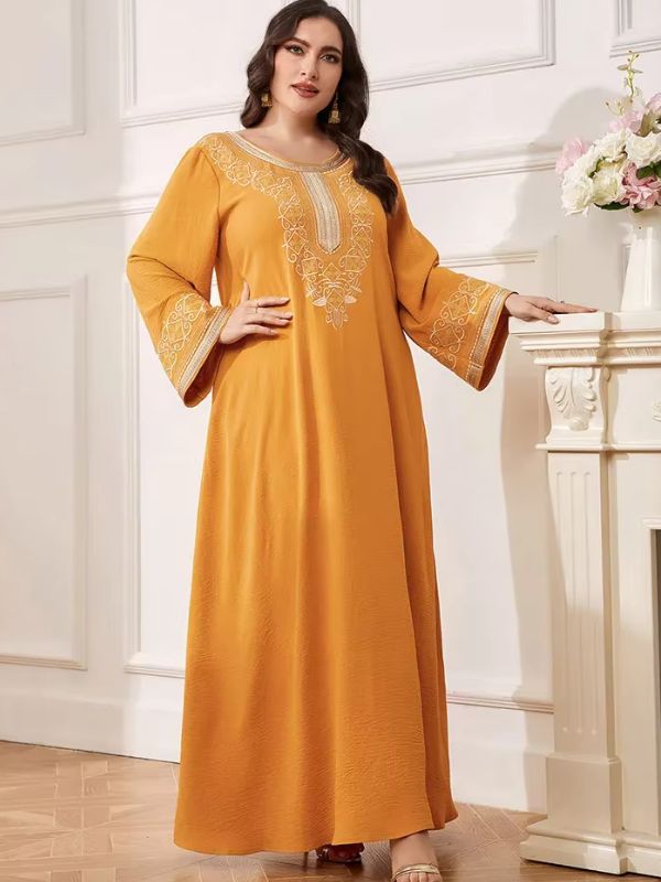 Robe marocaine safran, mains posées sur une cheminée, broderie du col et manches évasées