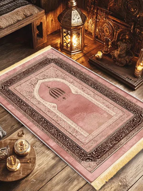 Tapis de prière vieux rose Rose d'Andalousie à franges, vu de biais sur un parquet près d'une lanterne allumée